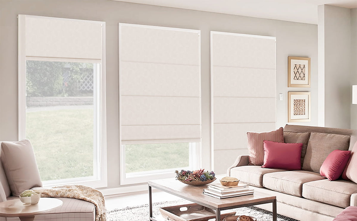 Cream Roman shades behind a living room sofa