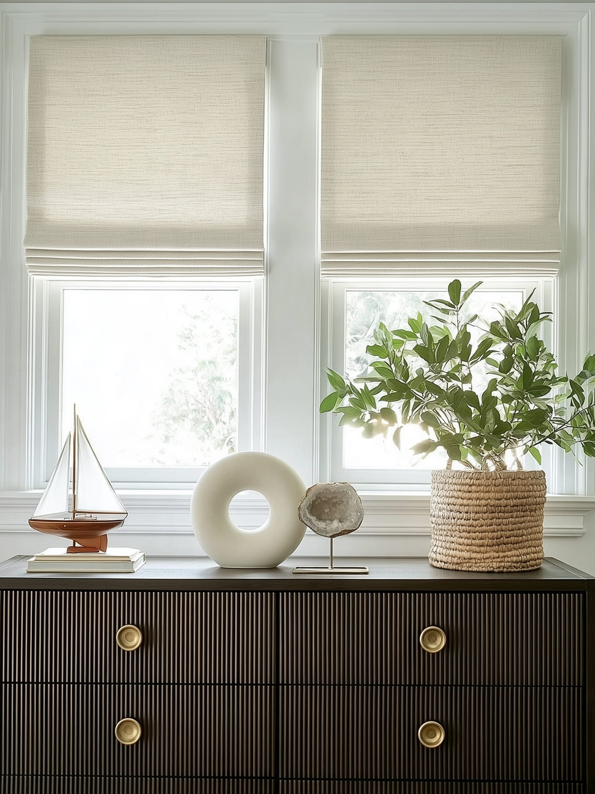 White Roman shades above a dark cabinet